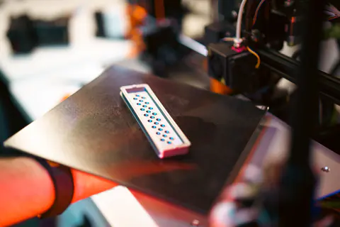 Mano che solleva un piano di stampa flessibile con un pezzo appena stampato