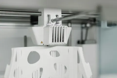 Dual-nozzle 3D printer head printing a detailed white part